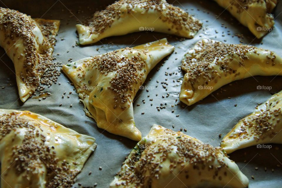 Close-up of homemade puff pastry with sesame seeds on baking sheet
