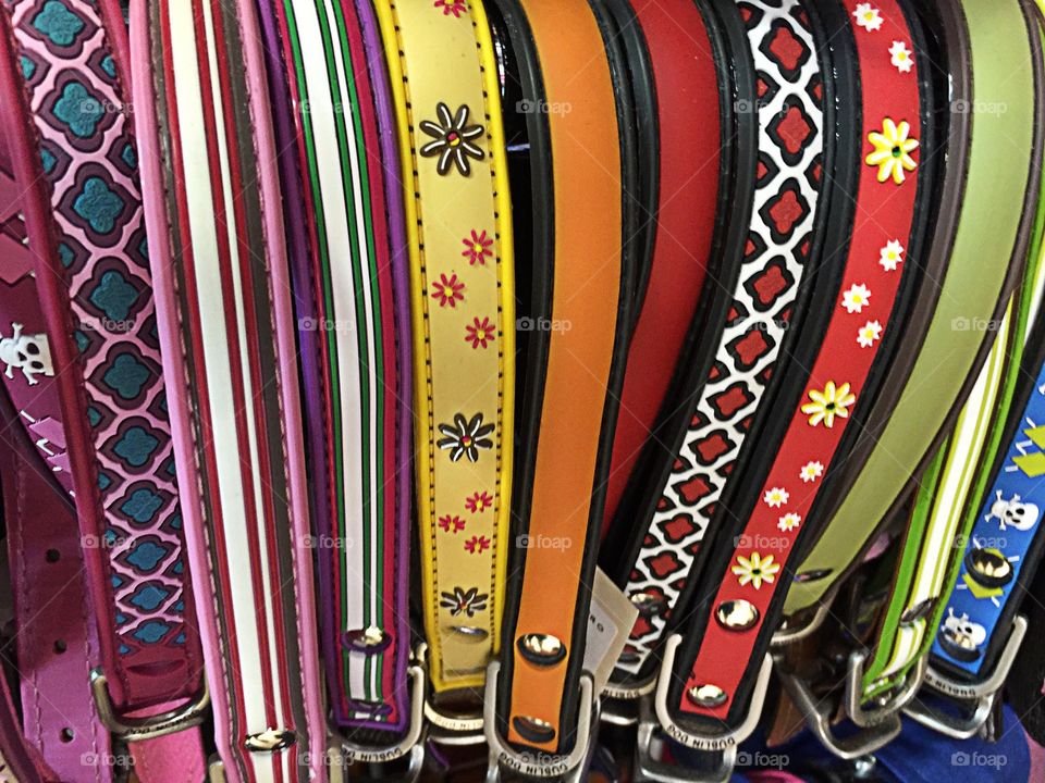 Belts on display in a rainbow of colors with fine details.