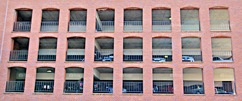 Row's of red brick windows with iron bars in a 6-story car garage in the state capitol of Sacramento California.