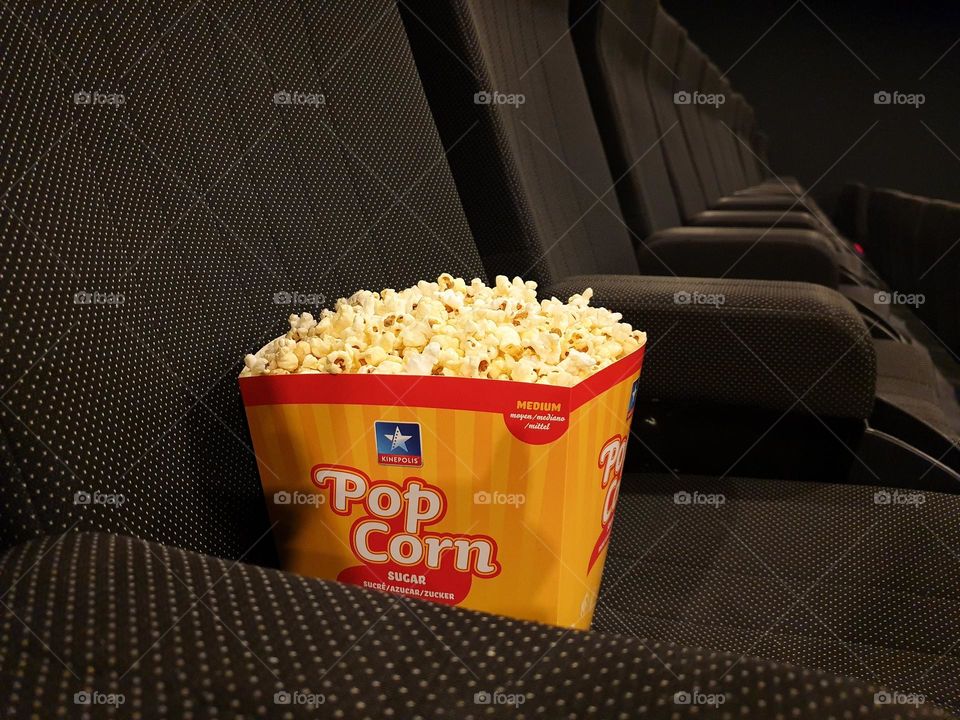 a portrait of a budget of popcorn on an empty seat in a cinema theater in an empty row.