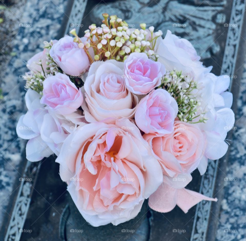 Closeup of a bouquet of pink roses from the top angle on a gravestone 