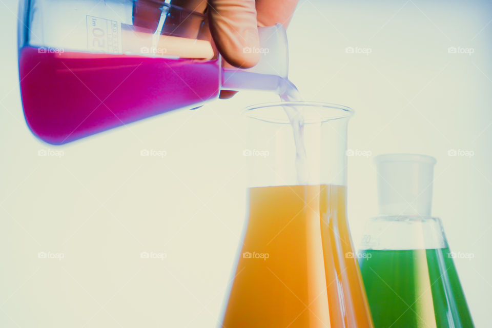 Woman using chemistry and science equipment filled with fluid