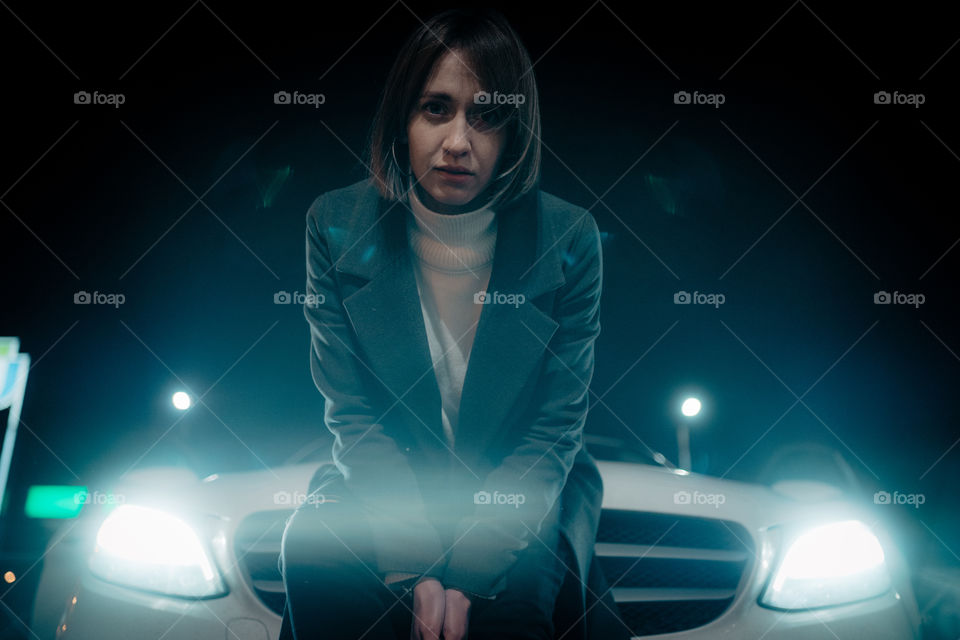 stylish woman in the car lights at night / movie scene