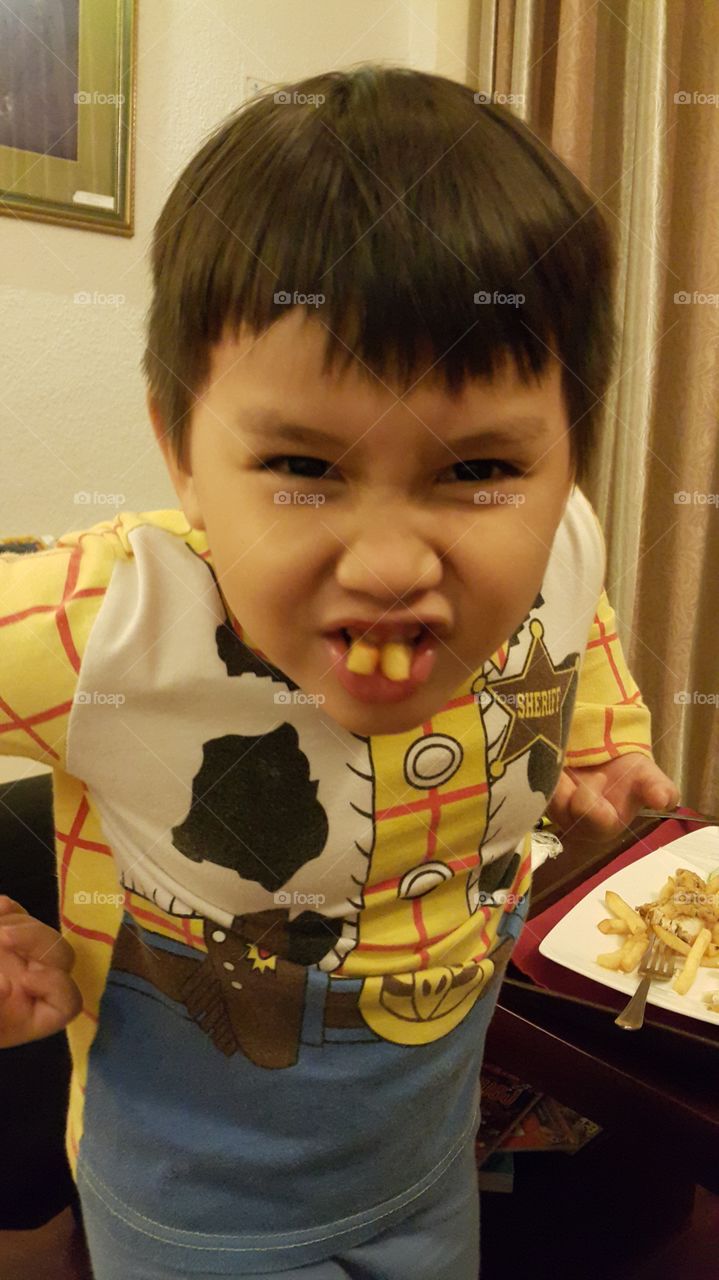 kid making funny face. French fries for teeth