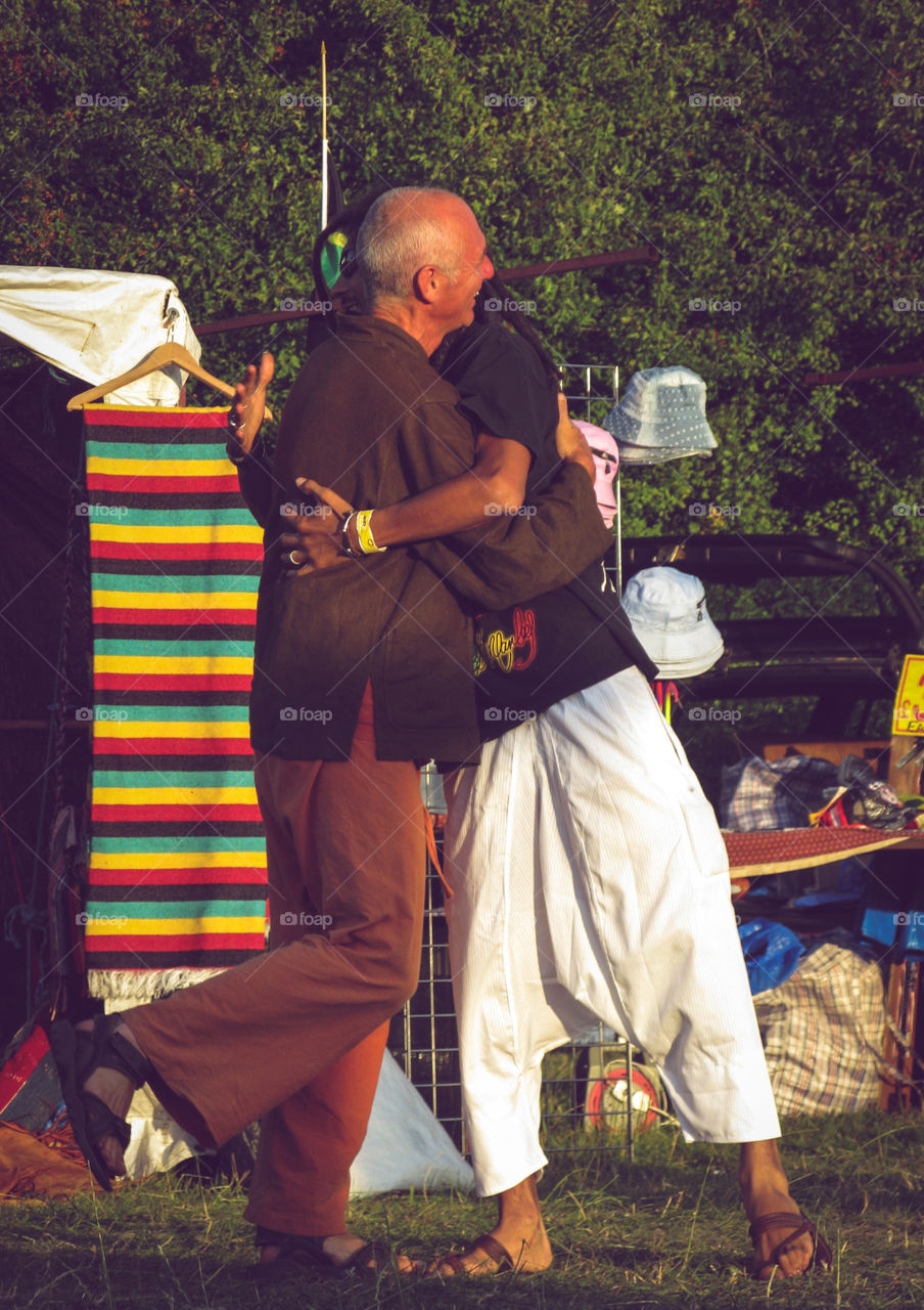 2 old friends great each other warmly at a summer festival