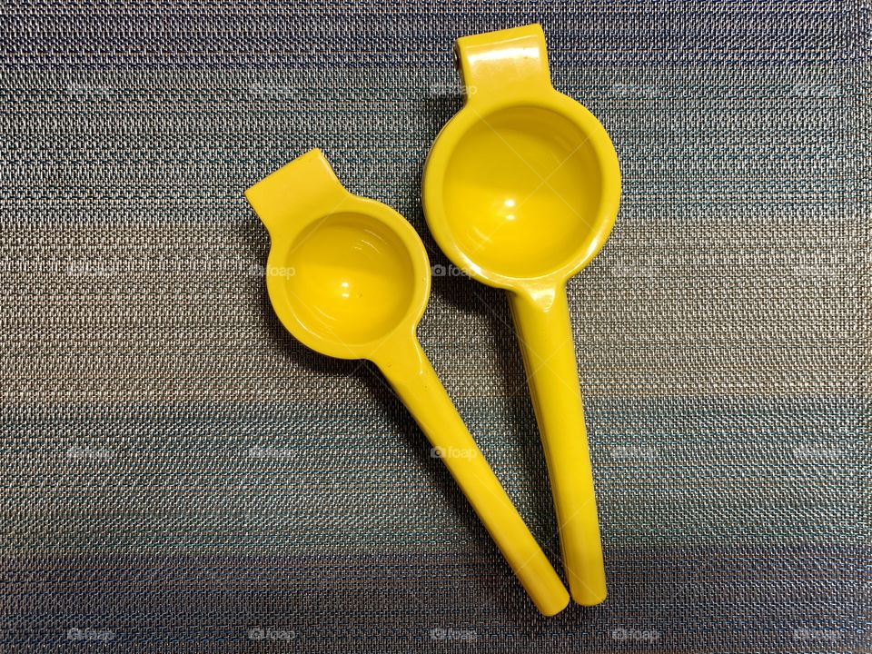 Lemon and lime squeezer, yellow, with sky blue place mat. Kitchenware. Hand held. Easy to use.