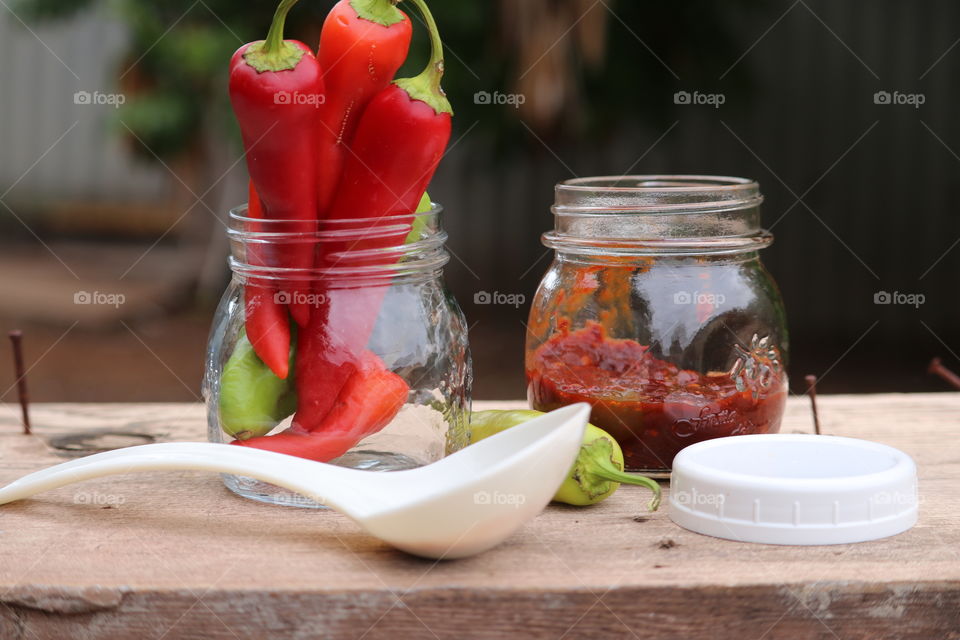 Homemade chopped red pepper preserves outdoor rustic image of jar, ladle, peppers