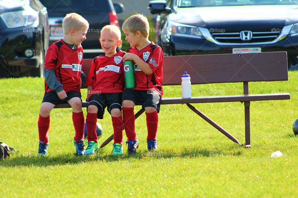 Boys on the Soccer Bench. Three young boys enjoy each other's company on the sideline