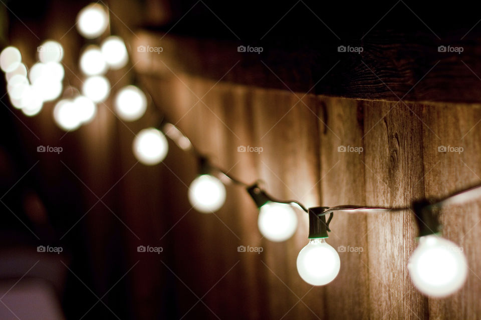 Round vintage styled incandescent bulbs strung along an old wooden fence