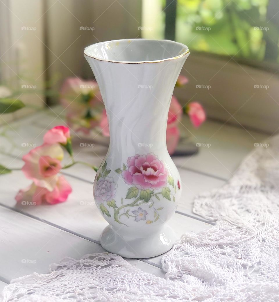 Old little porcelain vase with floral ornament on the lace