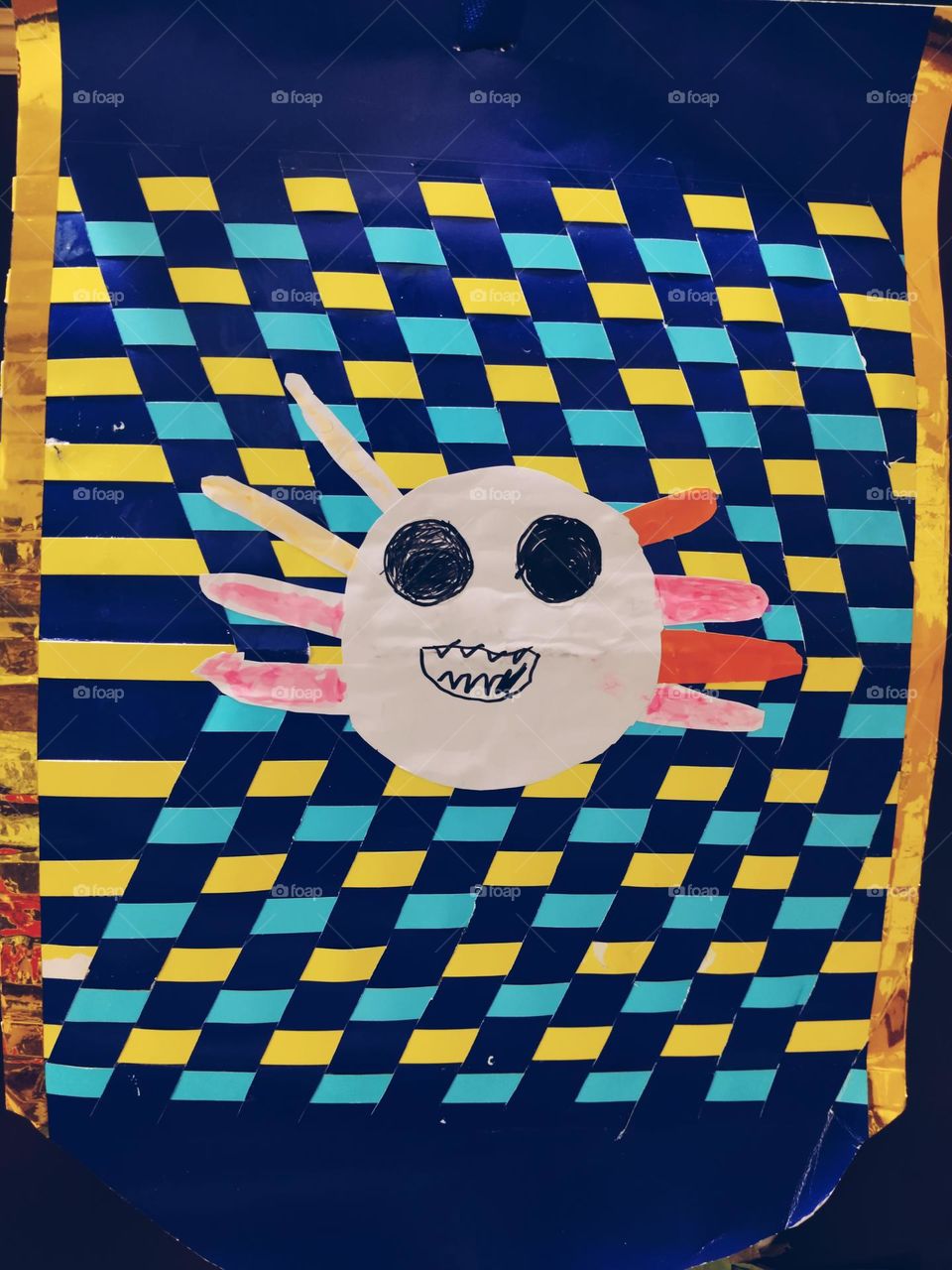 Children's creation: A toothy smiley face on a blue and yellow checkered background, full of fun and energy.