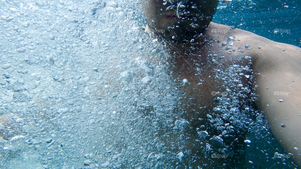 Man diving, male underwater smiling,swimming and relaxing in big blue sea with his camera