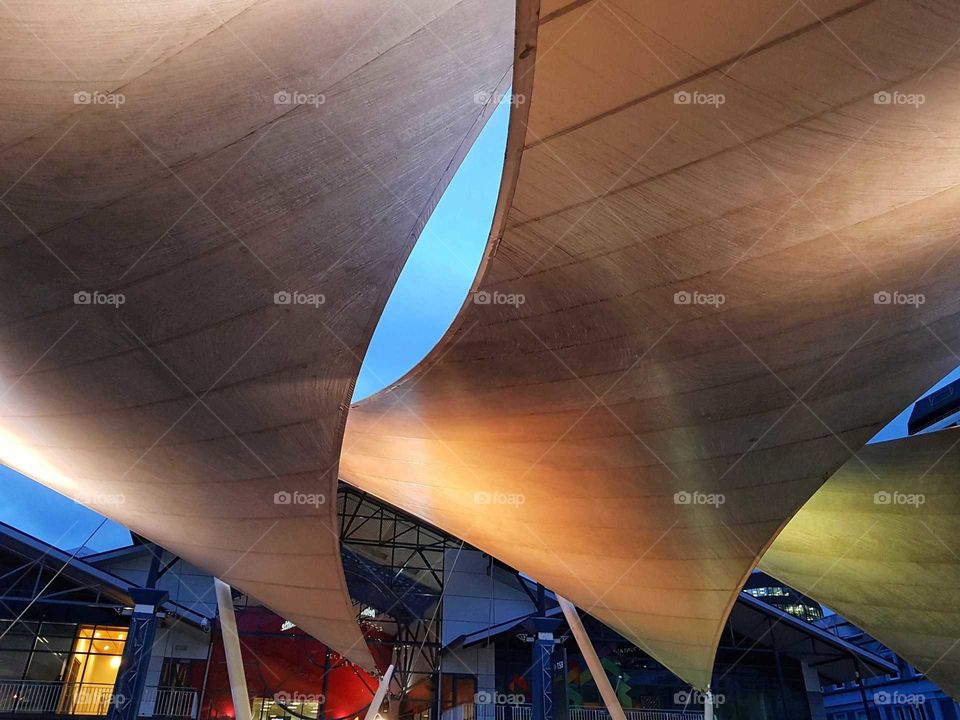 Shade sails at night in Wellington city by the harbour. Light reflects as night sets in.