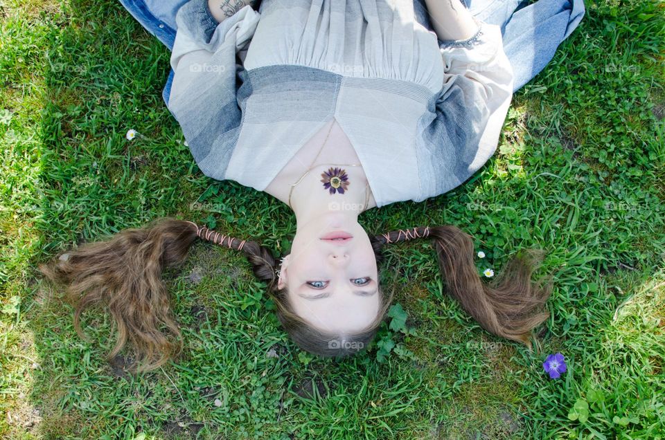 Portrait of beautiful natural woman lying on the field in green grass