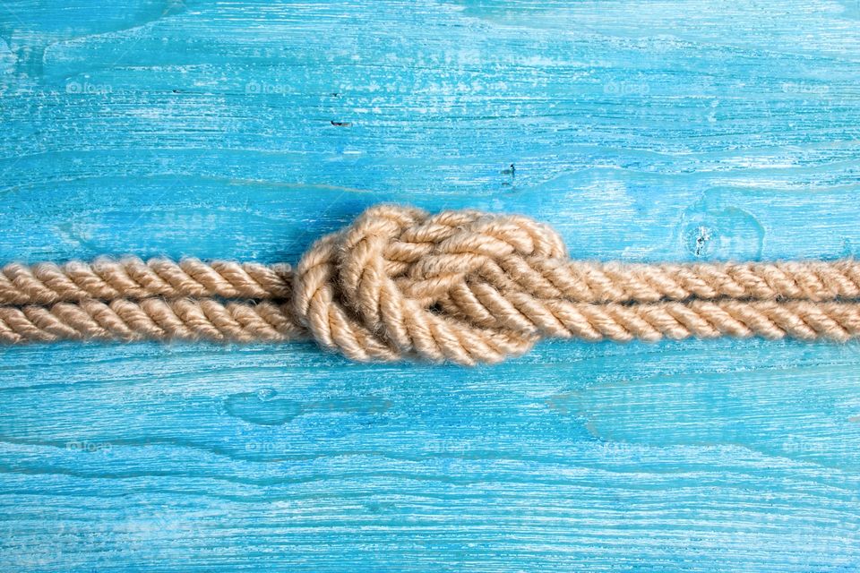 Knot on a rope on a wooden background.