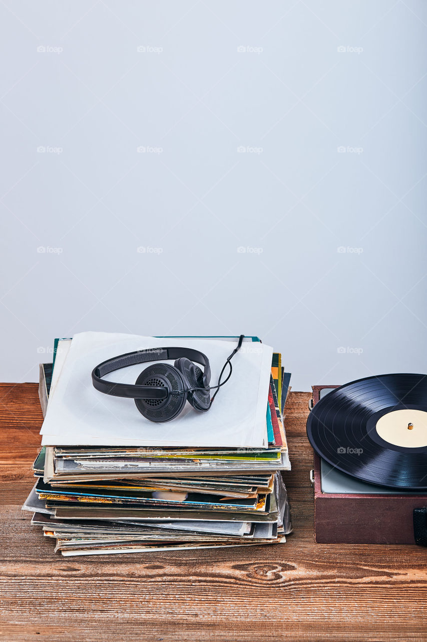 Stack of many black vinyl records, turntable vinyl player and headphones put on the stack. Classic stereo set. Candid people, real moments, authentic situations