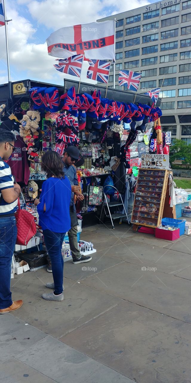 tourists at tourist souvenir stand in London on sunny day surrounded by English flags