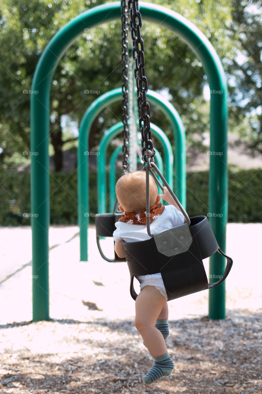 Dad pushing his son on the swing 