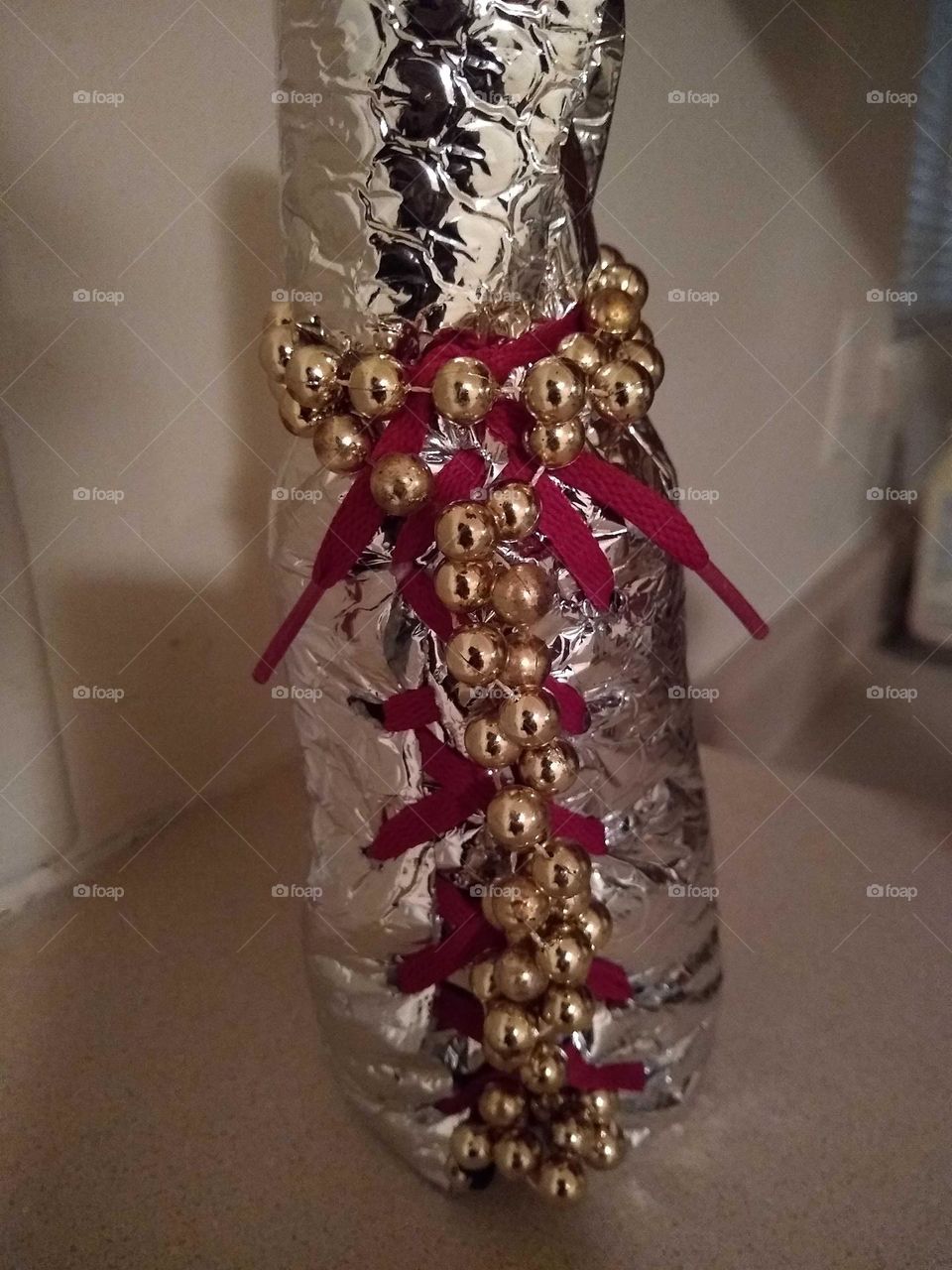 My handcrafted insulated vase with gold Mardi Gras Beads and red tie. My creation.