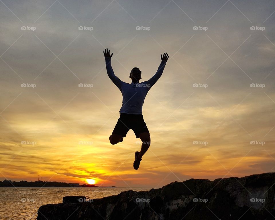 Man jumping on beach  against sunset sky