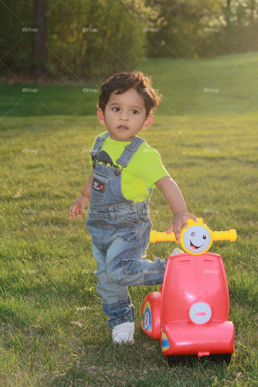 Toddler with his toy bike in a lawn