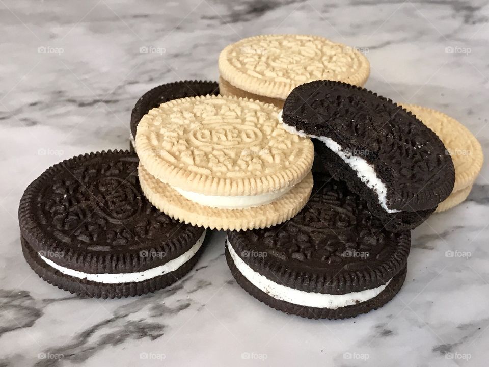 A pile of golden and chocolate double stuff Oreo cookies with a bite taken out of a cookie