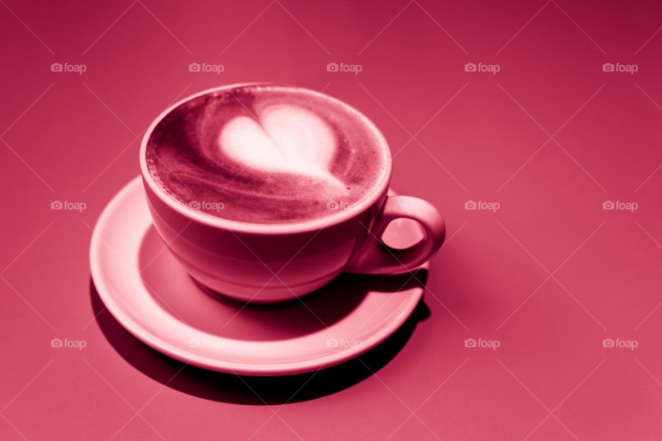 cup of cappuccino with white heart on viva magenta background