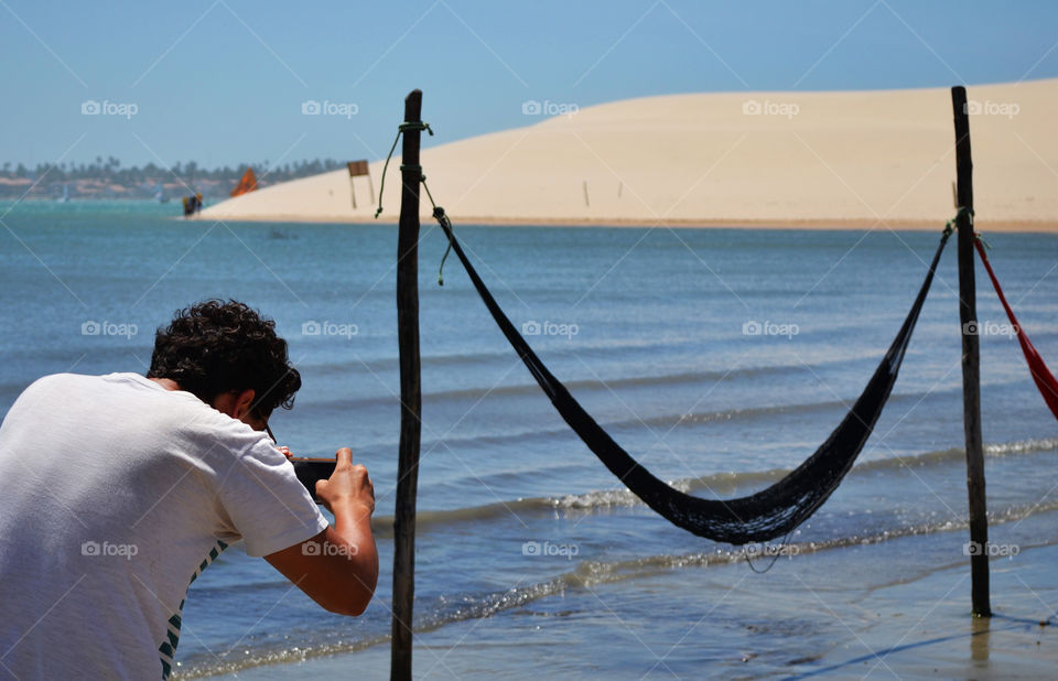 Man taking photos. Man taking photos of hammocks on the Beach