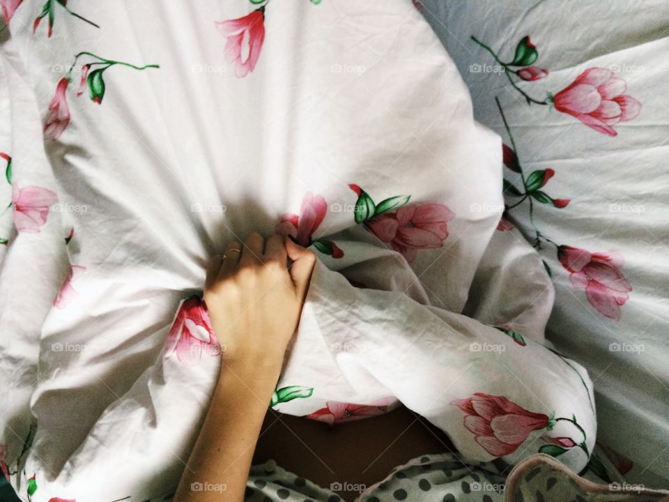 Young woman laying in bed in the morning in her warm and cosy polka dot pajamas