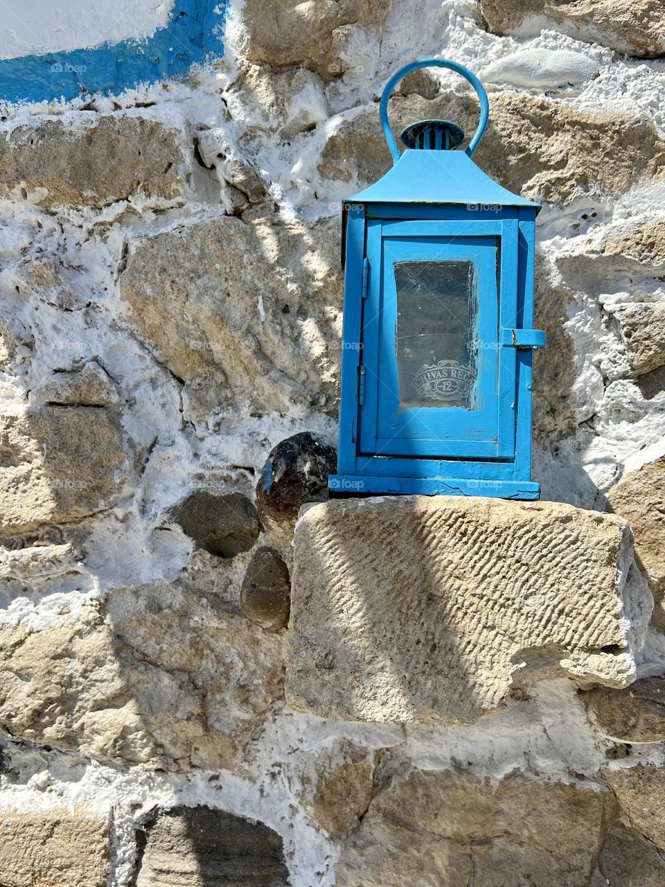 Blue lantern over stone in the wall 