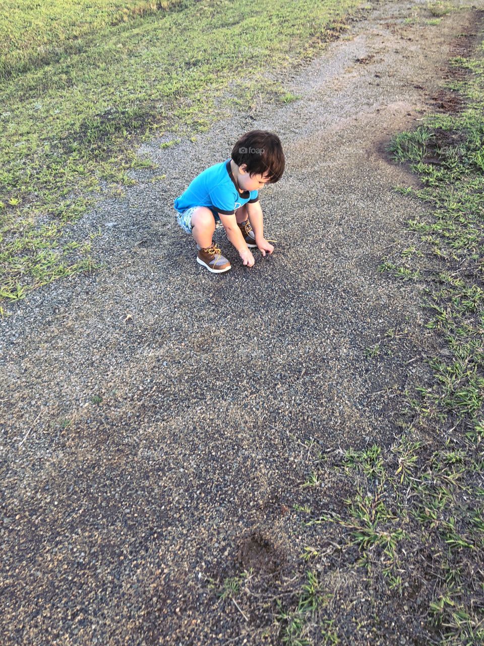 Little boy playing with the gravel stones. 
