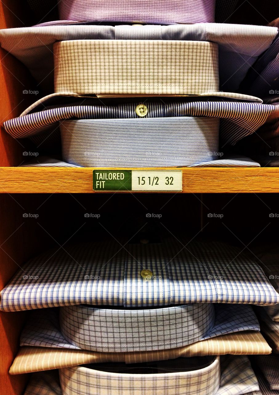 Shelves of colorful button-down shirts in a men's clothing store.