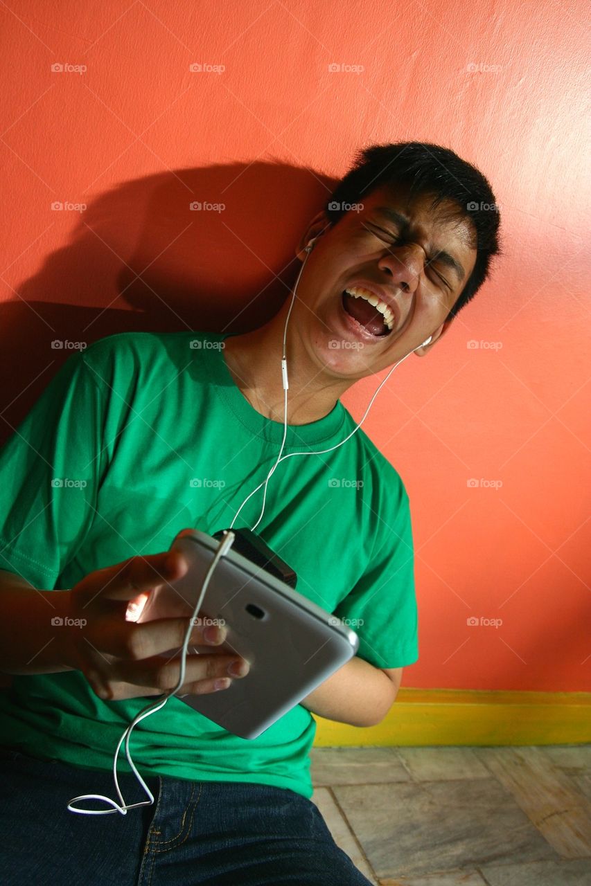 young asian teen listening to music on a tablet