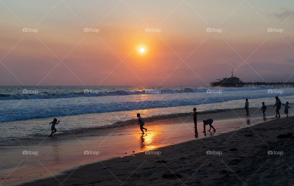 Kids enjoying the summer beach at sunset 