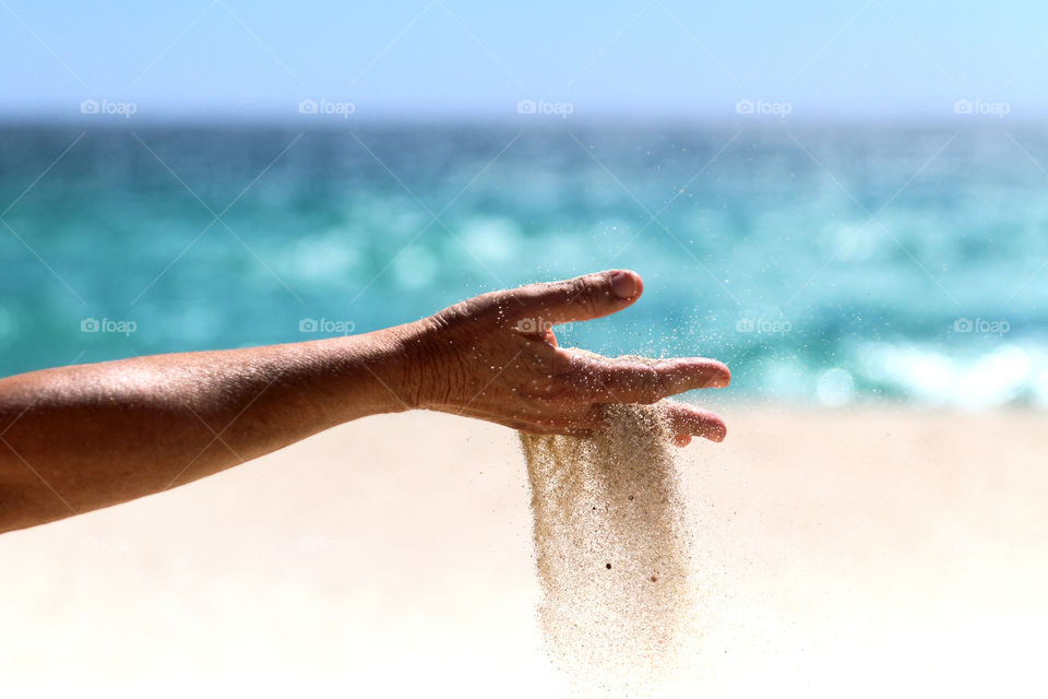 sands of time running through fingers at a beautiful beach
