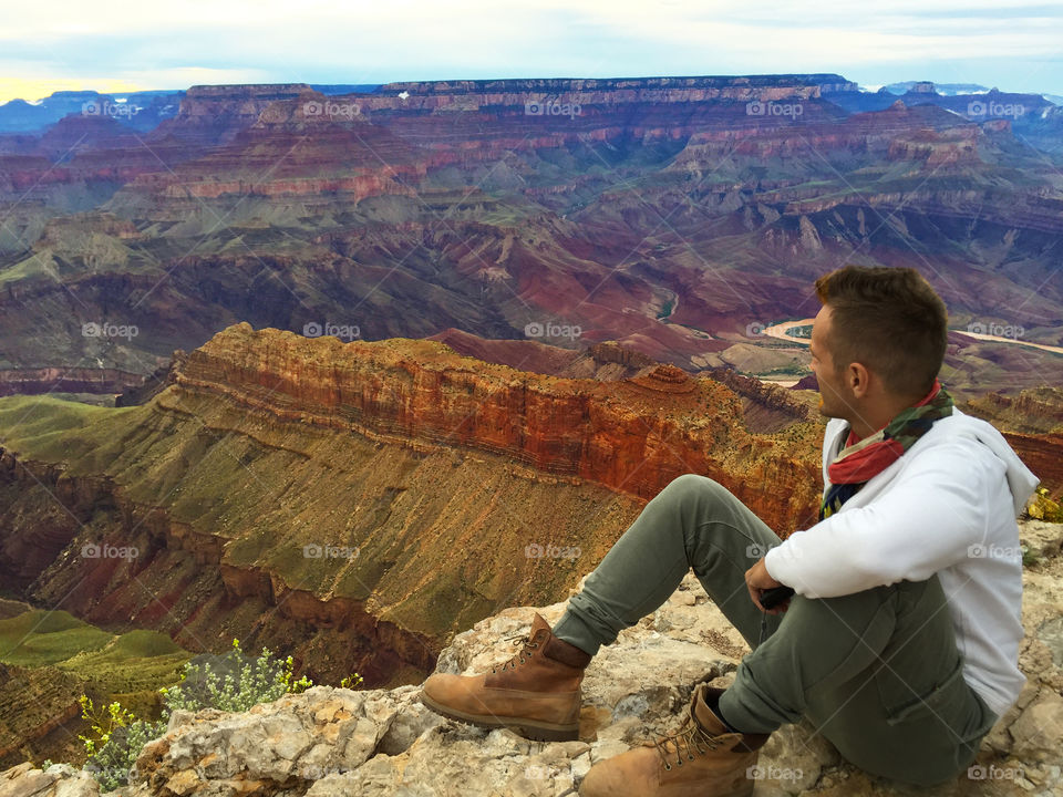 Man sitting on edge of Grand Canyon South rim, Arizona