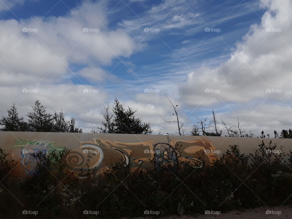 Graffiti in shade with clouds in sky