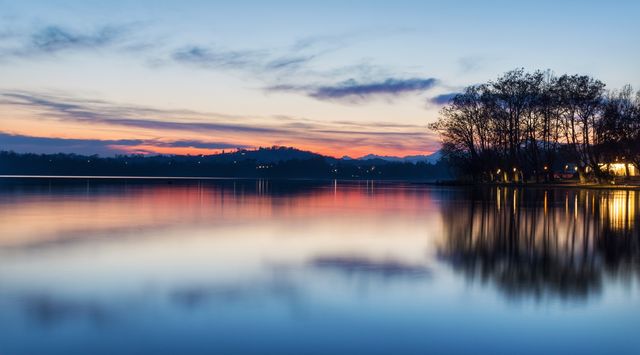 Sunset on a lake with a colorful reflection of the sky, the clouds and the panorama on the water