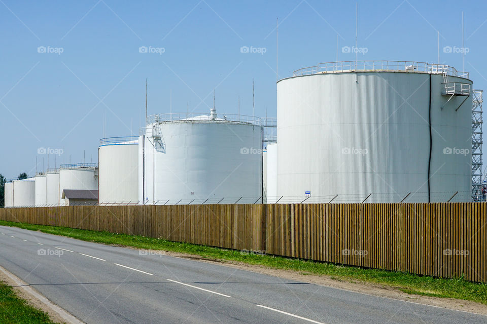 white cylindrical storage tanks for petroleum products against a blue sky