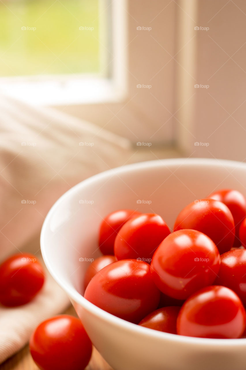 Bowl of tomatoes. White bowl with tomatoes and a garden background