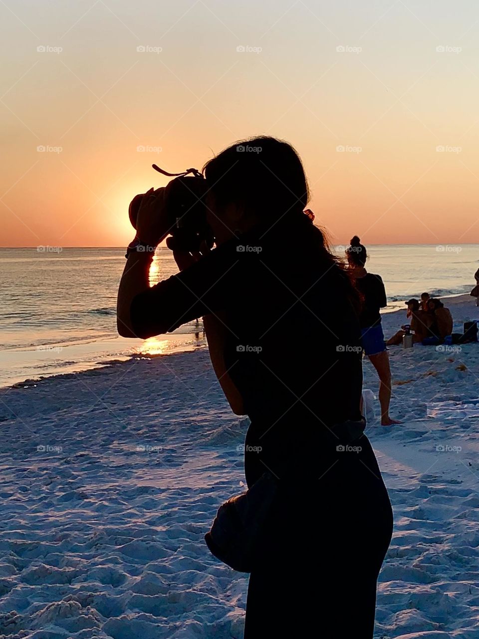 While standing on a sandy beach on the Gulf of Mexico, a Video Creator records a beautiful descending sunset