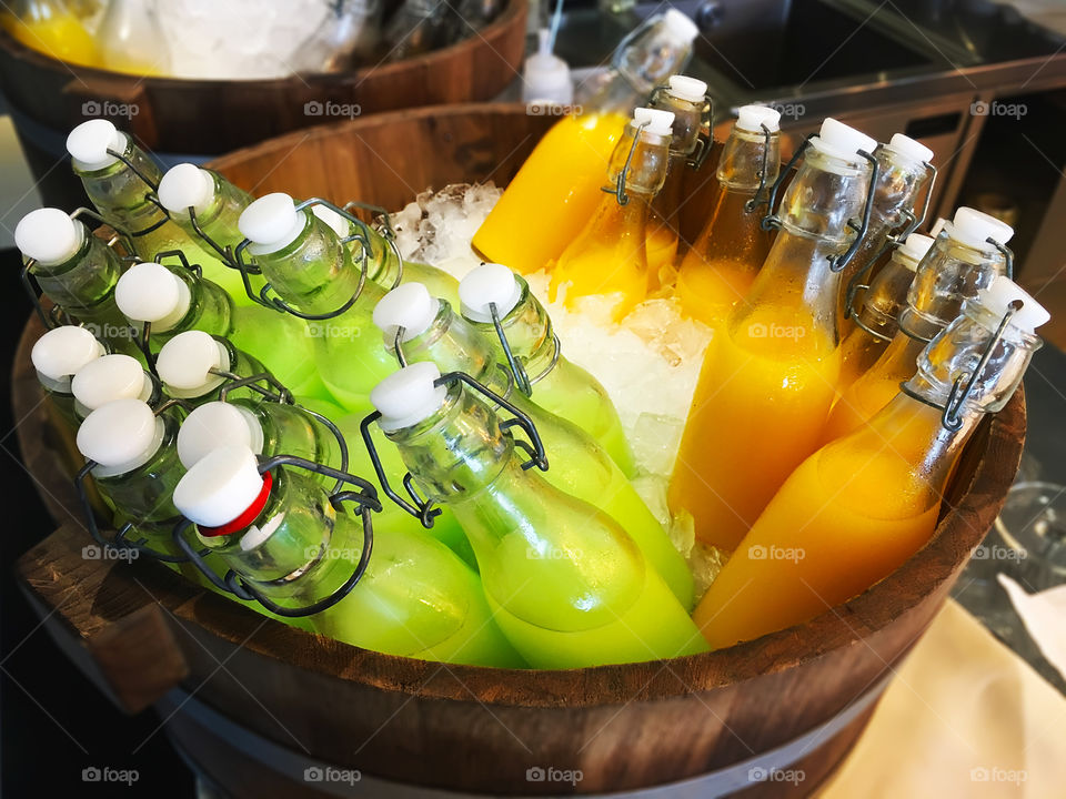 Bottles of guava and orange juice in the barrel with ice 