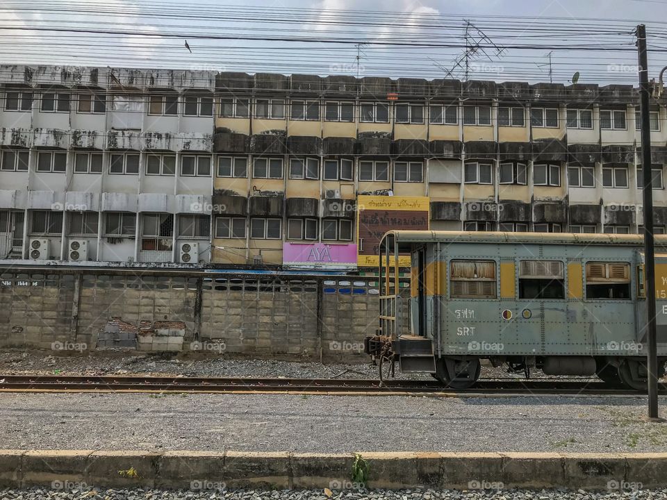 Old railway carriage in front of rundown building at Phitsanulok railway station, Thailand 