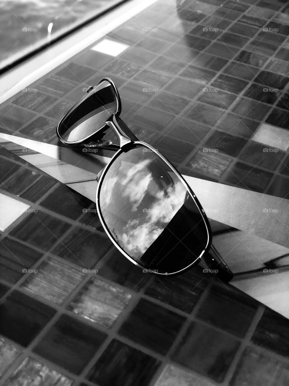 Sunglasses sitting on table about to be picked up. 