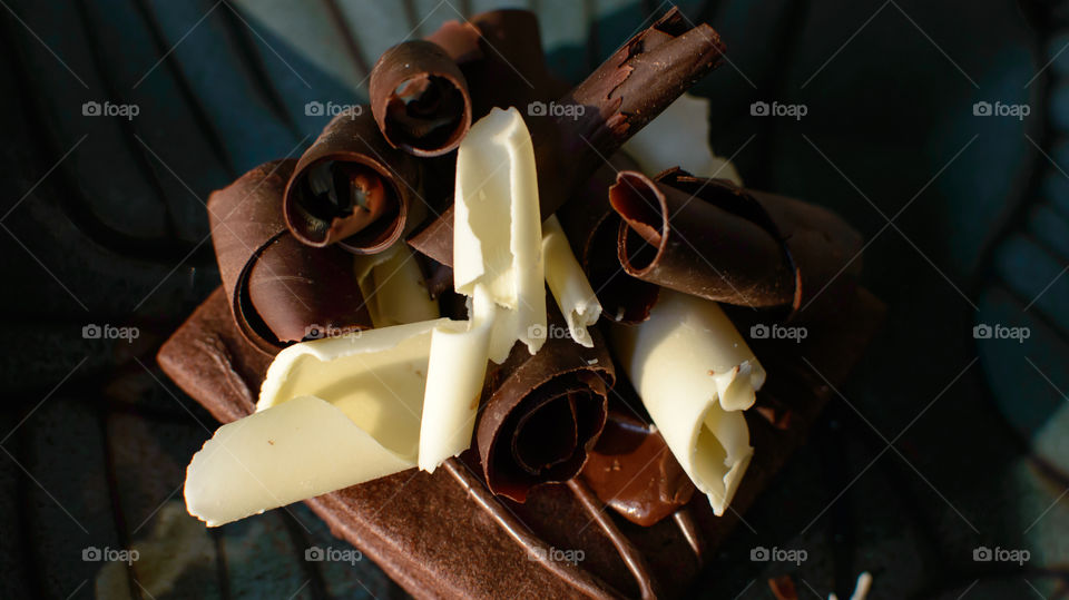 Closeup of dark rich chocolate shavings and white chocolate curls on top of cocoa cookie with fudge high angle view epicure dessert photography