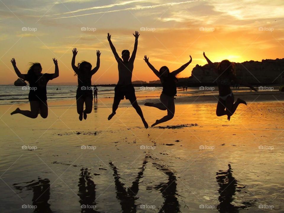 Five friends shapes jumping on a sunset background at the beach
