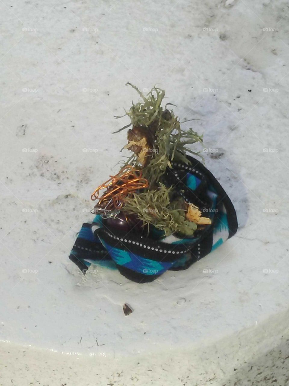 Paying respect to the spirt life by a gift offering. French moss with copper and a piece of material is left by a visitor to the cemetery