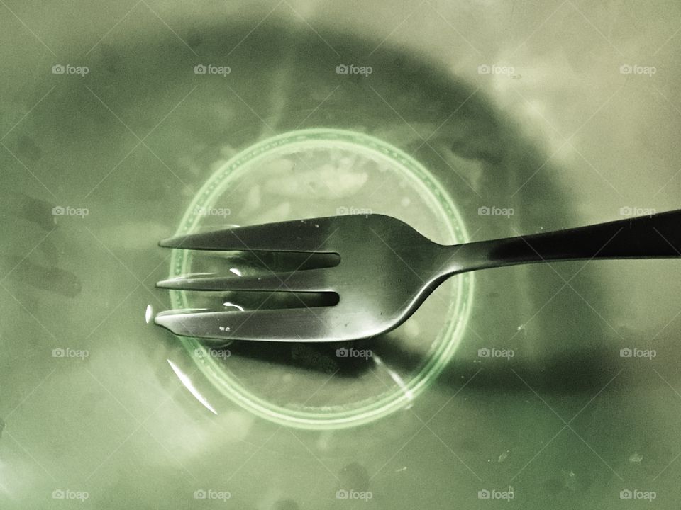 An empty green plastic bowl with a fork.