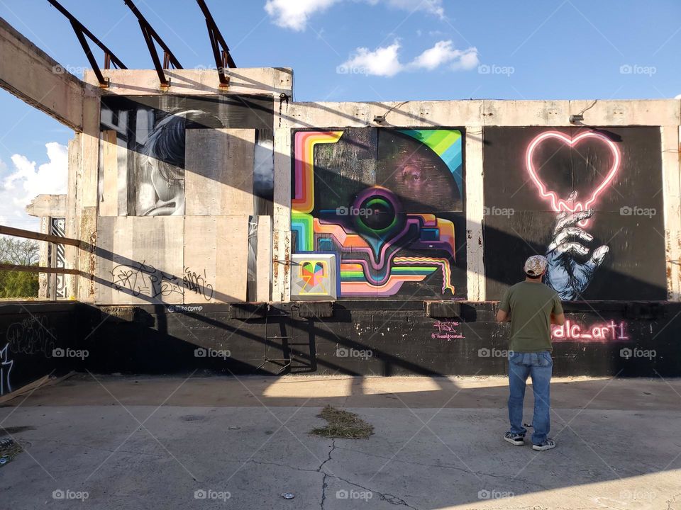 A man admiring the art at an abandoned urban outdoor art gallery.