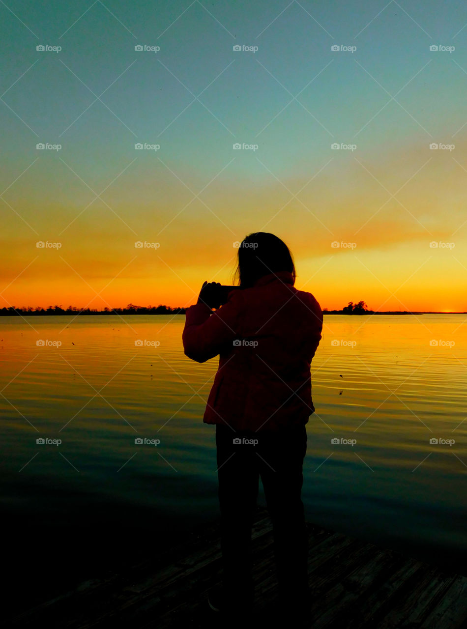 Taking picture of a woman taking a picture of s beautiful sunset!